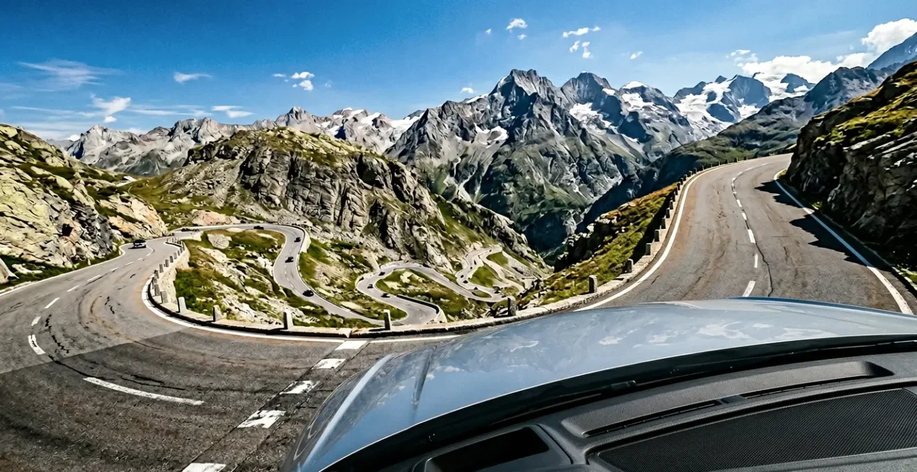 Steile Alpenpassstraße mit Serpentinen bei Sommerhitze, Fokus auf Motorhaube eines fahrenden Autos