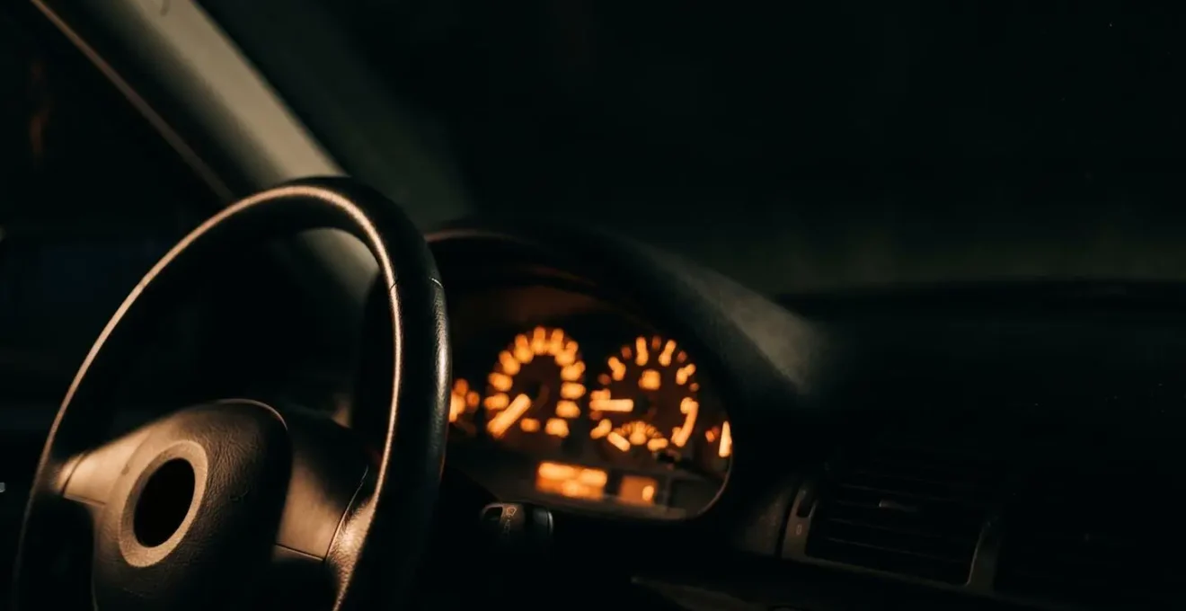 Dezent beleuchtetes Auto-Cockpit mit gedimmten Instrumenten während Nachtfahrt