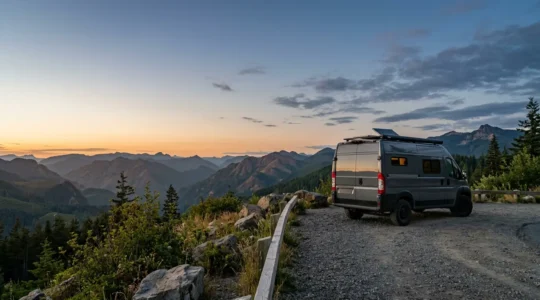 Ein Wohnmobil steht bei Sonnenuntergang auf einem ruhigen Naturparkplatz umgeben von Bergen und Wäldern