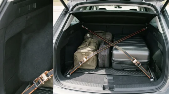 Nahaufnahme eines fest verzurrten Koffers im Fahrzeugkofferraum mit Spanngurten an Zurrösen, demonstriert professionelle Ladungssicherung für sichere Autobahnfahrten