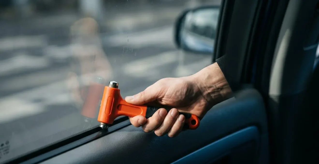 Dramatische Nahaufnahme der korrekten Technik zum Einschlagen einer Auto-Seitenscheibe mit Nothammer